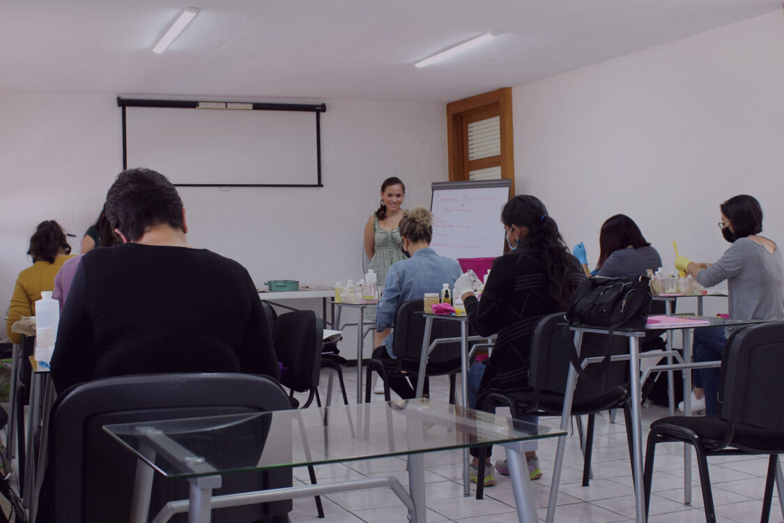 Tallerista impartiendo una capacitación profesional en una sala de Sinergia Espacios en Puebla, con asistentes atentos y espacio moderno.